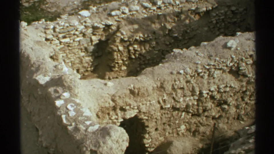 1972 Arizona 8mm frame showing a trench with rough masonry or adobe remains, stones, soil, and a shadowed opening near the lower edge.