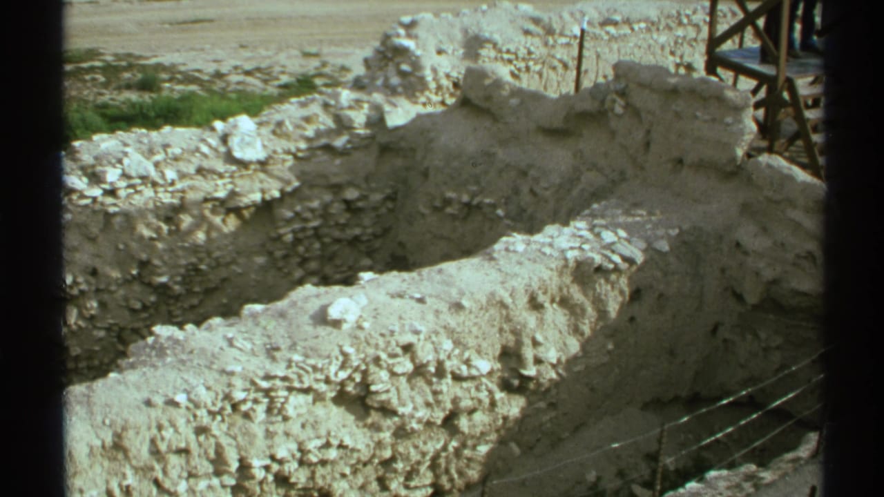 Excavated stone walls with rubble and a wooden support structure near the edge.
