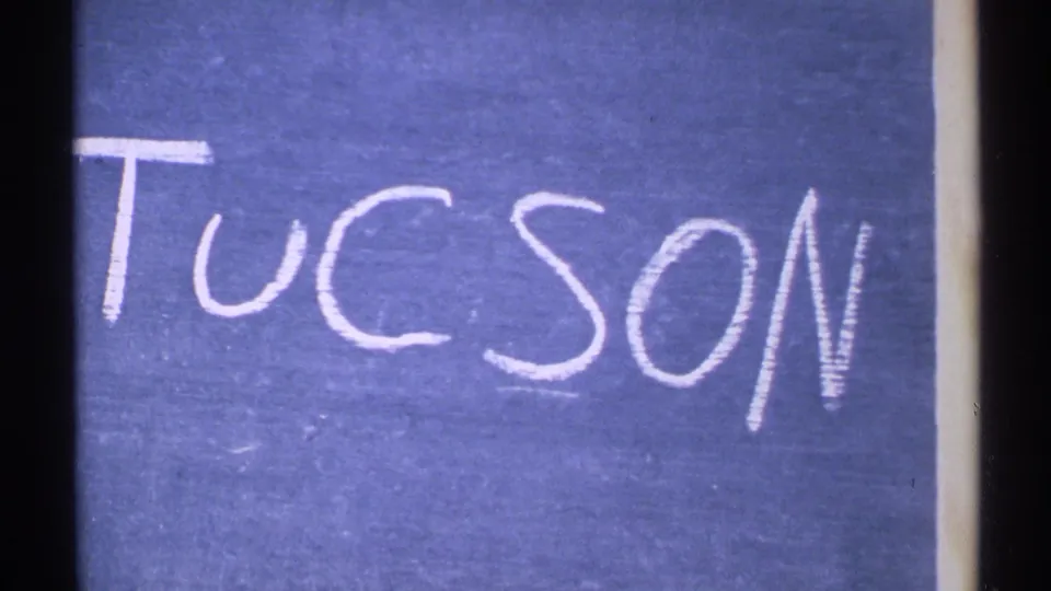 1972 home-movie title card with the word Tucson written in white chalk on a blue surface.