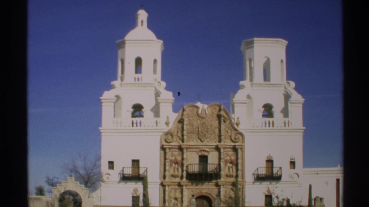 White Spanish Colonial church facade with two bell towers under a blue sky.