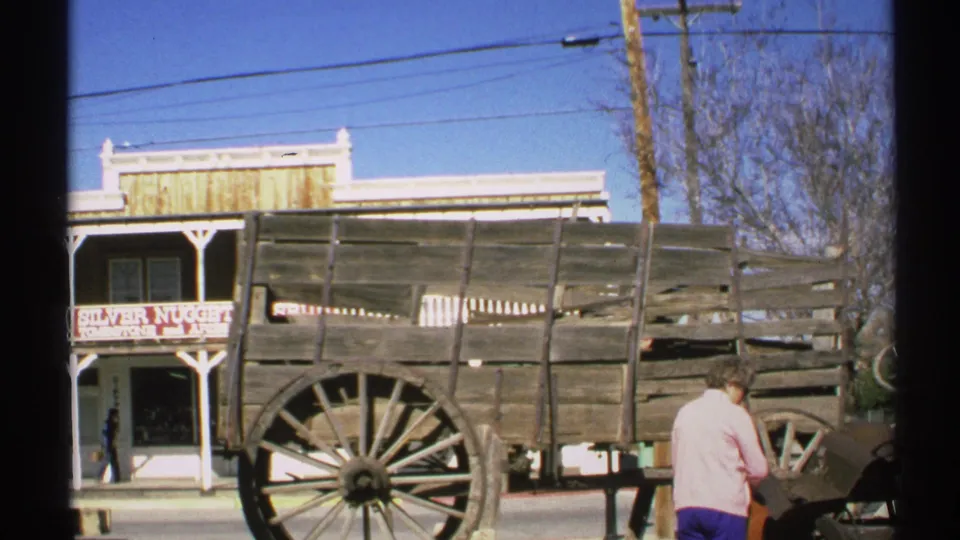 1972 Arizona home-movie frame of a wooden wagon display outside a Silver Nugget storefront, with one visible person and street details behind it.