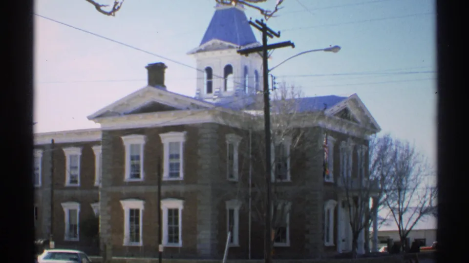 The final 1972 Arizona frame shows the stone building and blue steeple from across the street, with cars and utility lines nearby.
