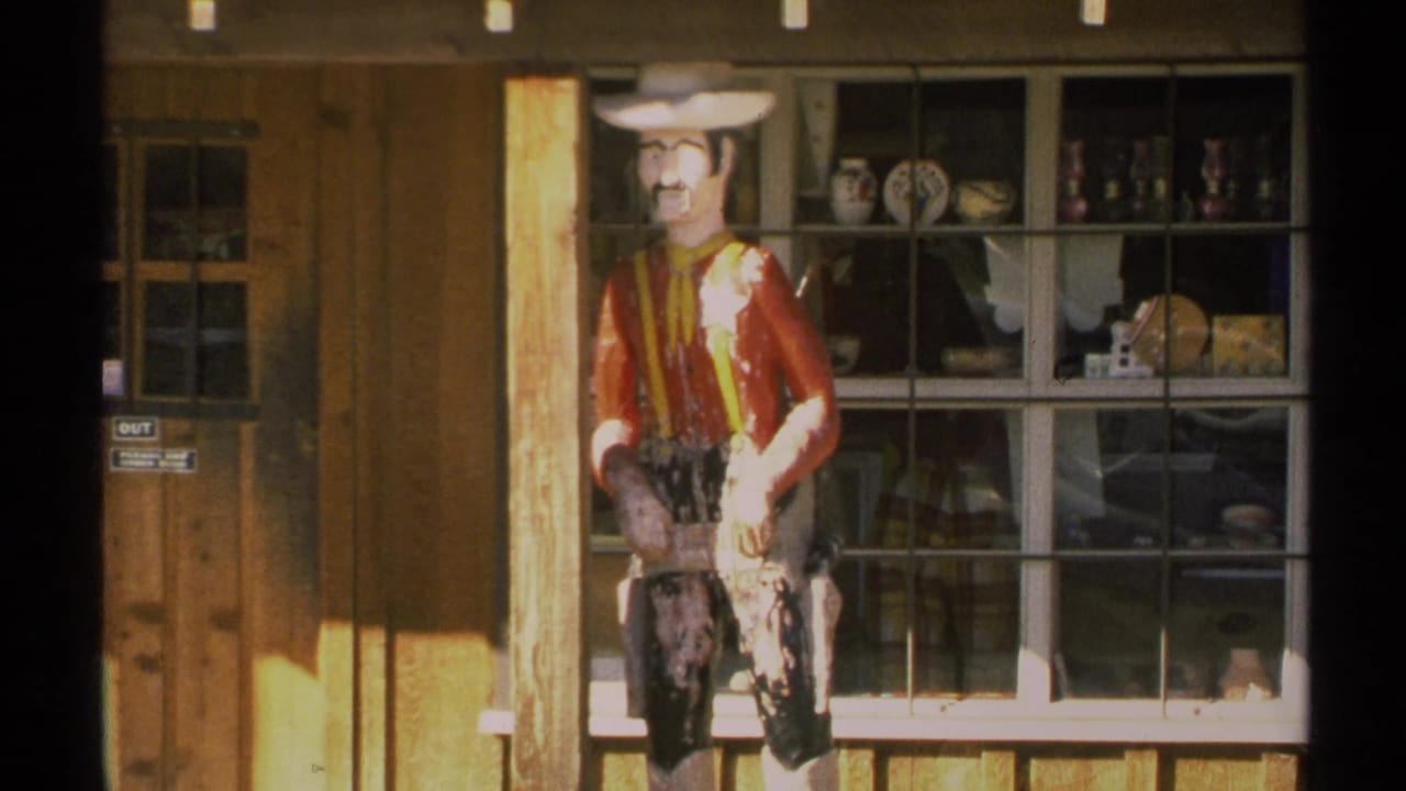Cowboy mannequin in front of a rustic shop window with pottery on display.