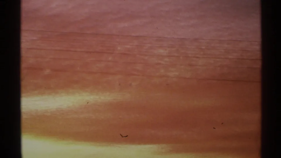 1972 Arizona 8mm frame focused on red, orange, and yellow cloud bands at sunset, with visible film grain and edge shading.