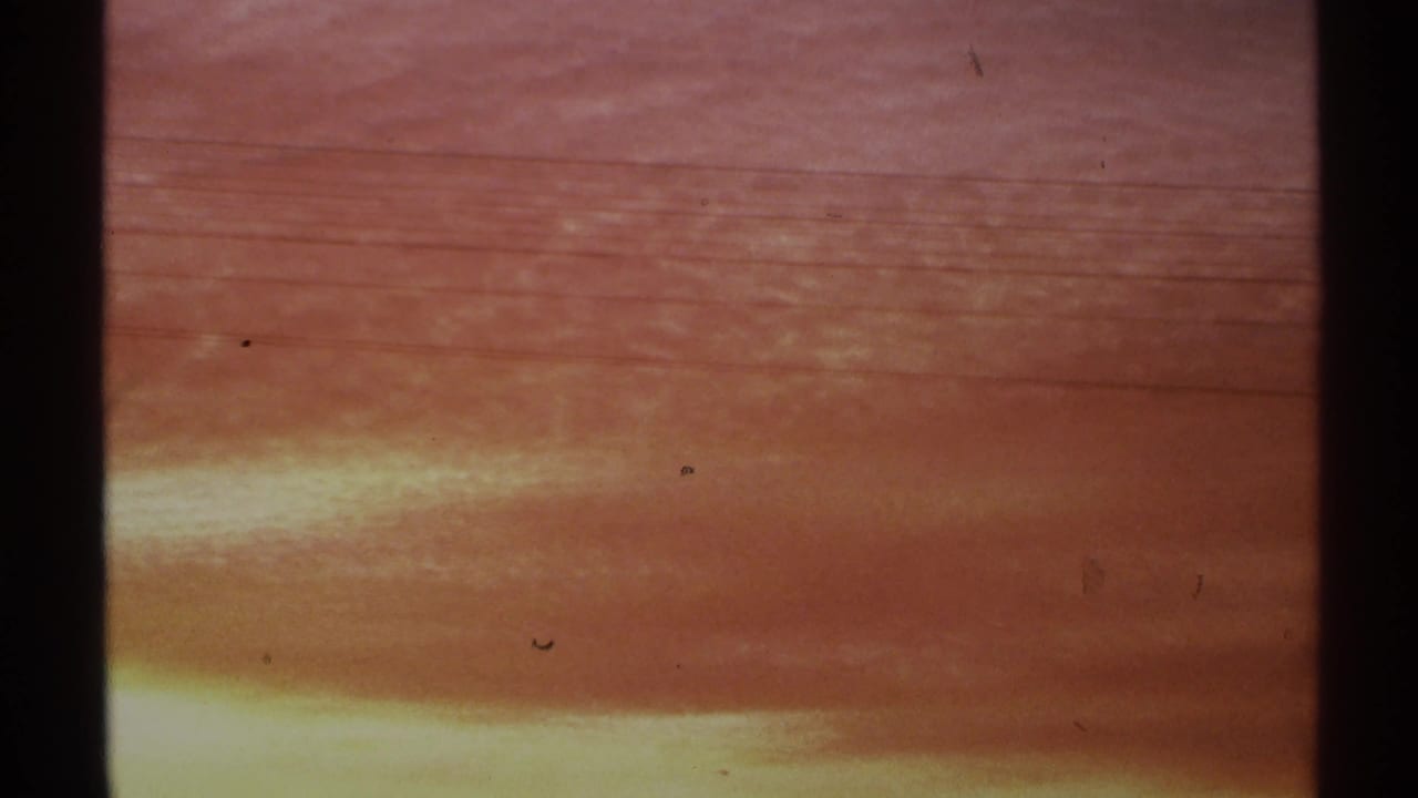 Warm orange sunset sky with dark vertical film-edge shadows and faint horizon glow.