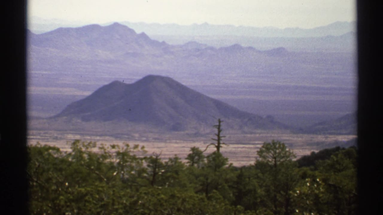 Distant conical hill amid layered Arizona mountain ranges and desert vegetation.
