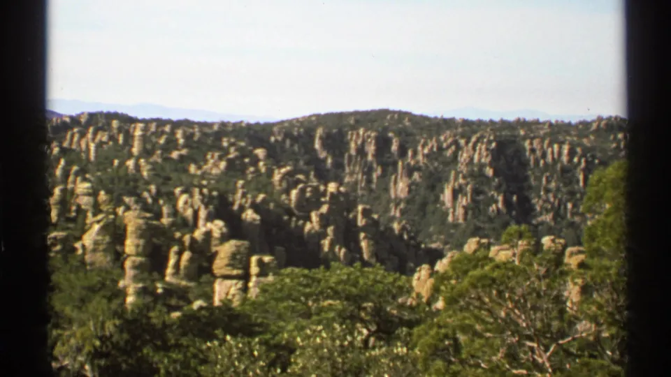 Vintage Arizona landscape view with clustered stone spires, forested canyon floor, and soft 8mm exposure.