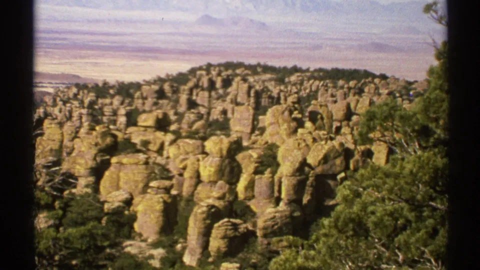 Final 1972 Arizona 8mm frame holds on tan rock formations, scattered trees, and distant terrain with visible film-frame borders.