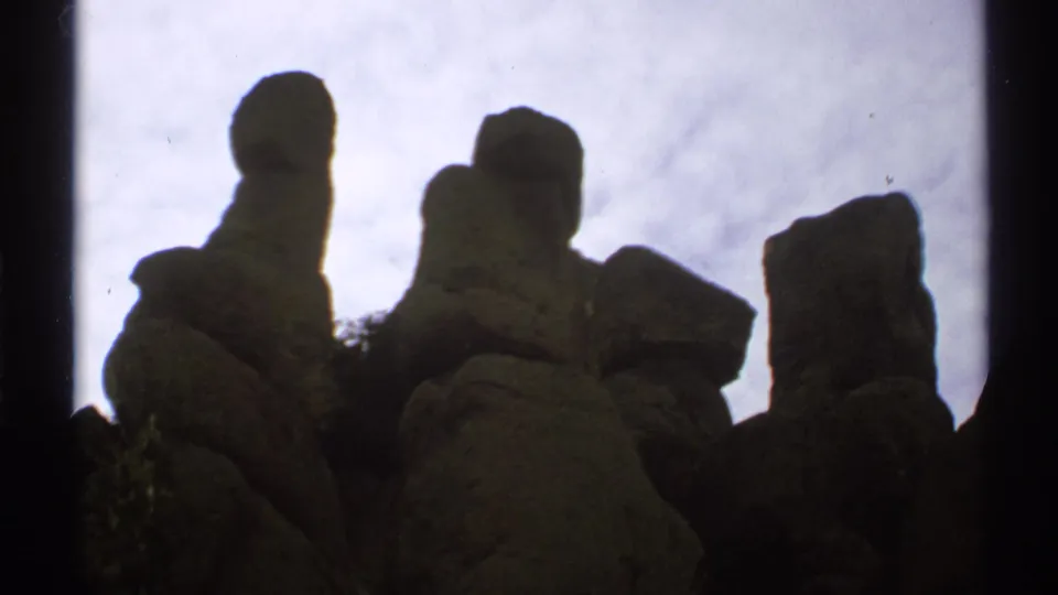 1972 Arizona home-movie view of several irregular rock formations grouped against a bright, overcast sky.