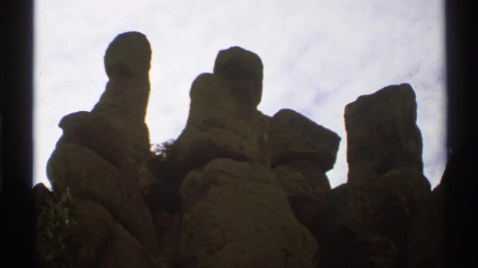 1972 Arizona 8mm frame with massive weathered boulders and upright rock columns filmed from a low angle.