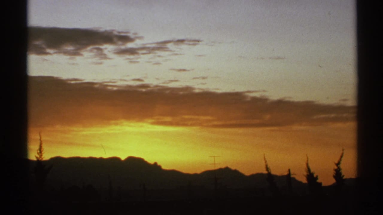 Glowing sunset sky over a dark mountain ridge with clouds and frame edges.