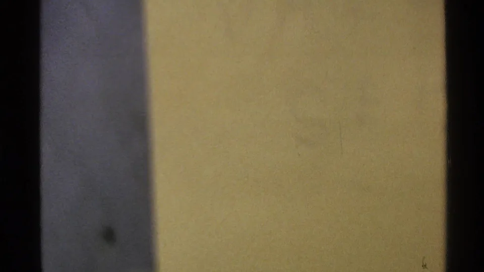 Soft, under-detailed frame showing a yellow surface beside a dark vertical border in the 8mm reel.