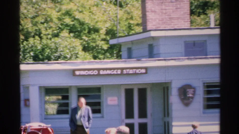 Soft 8mm view of the Windigo Ranger Station, showing the building sign, entrance, and visitors at the edge of the frame.