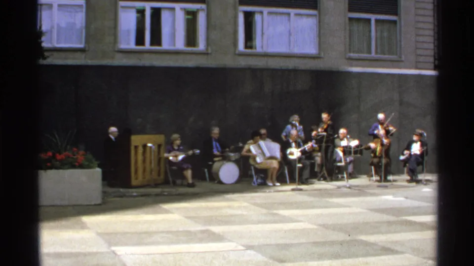 1972 Isle Royale courtyard music scene with adult performers seated and playing instruments.