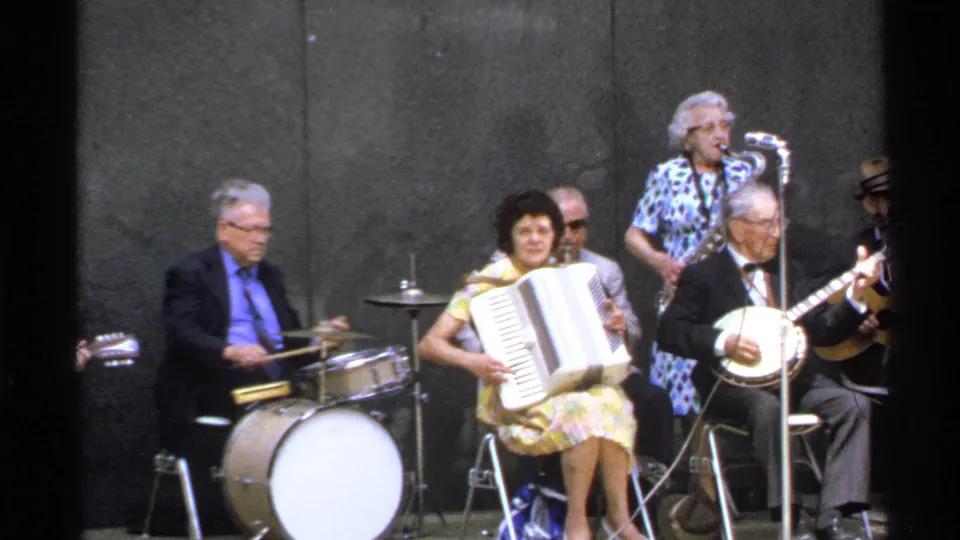 1972 Isle Royale home-movie frame centered on accordion, drums, banjo, and a standing singer with microphone.