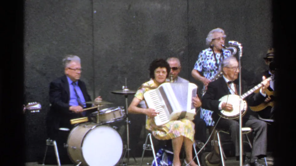 Final 1972 Isle Royale frame showing the small ensemble mid-performance with accordion, drum kit, banjo, and microphone.