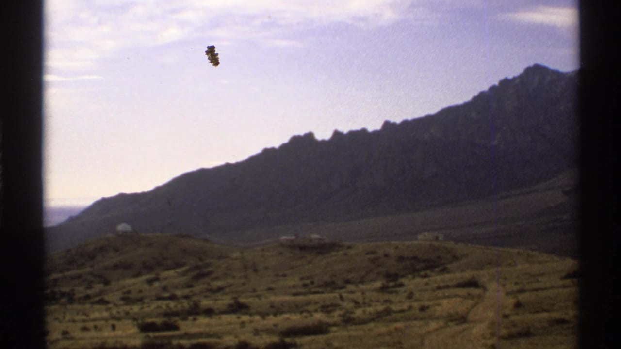 1972 New Mexico desert landscape with mountains, scrub, pale sky, and dark 8mm frame edges.