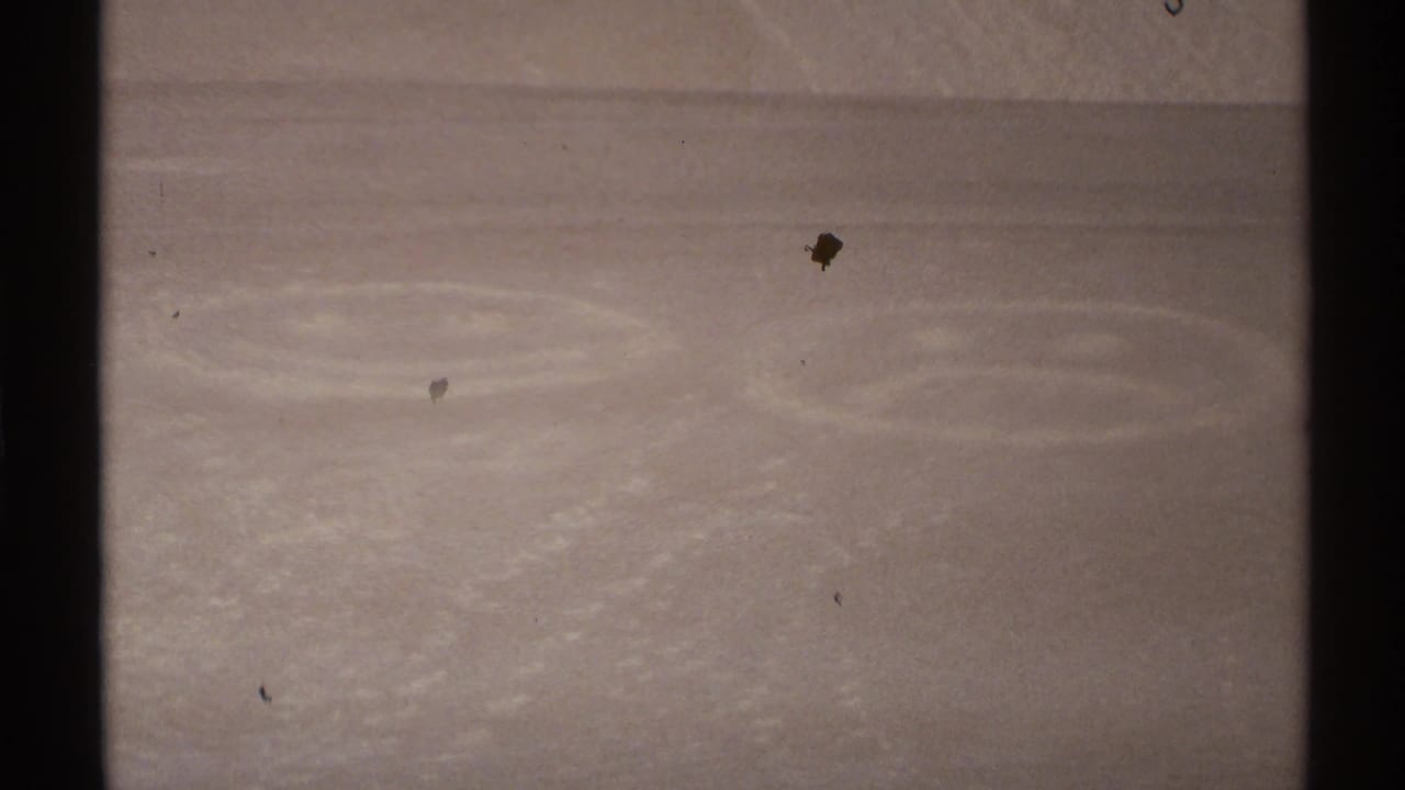 Pale sloped surface with faint circular marks below a dark blue sky band.