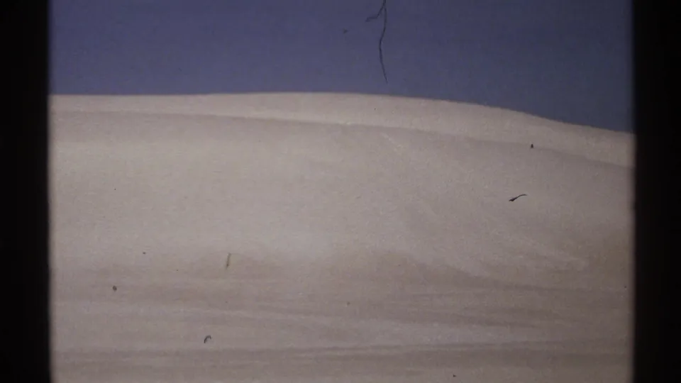 1972 New Mexico 8mm frame with a pale ridge-like surface and dark blue sky, with no people or structures visible.