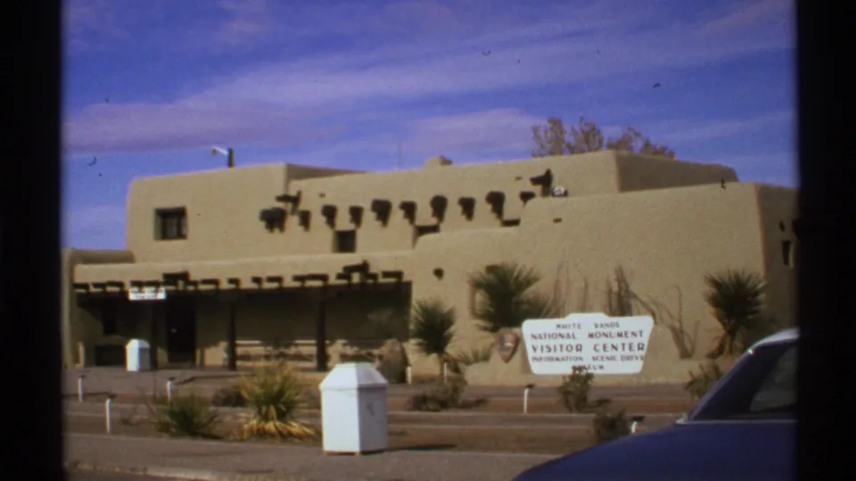 8mm frame of the White Sands visitor center exterior, with sign and desert planting visible in 1972 footage.