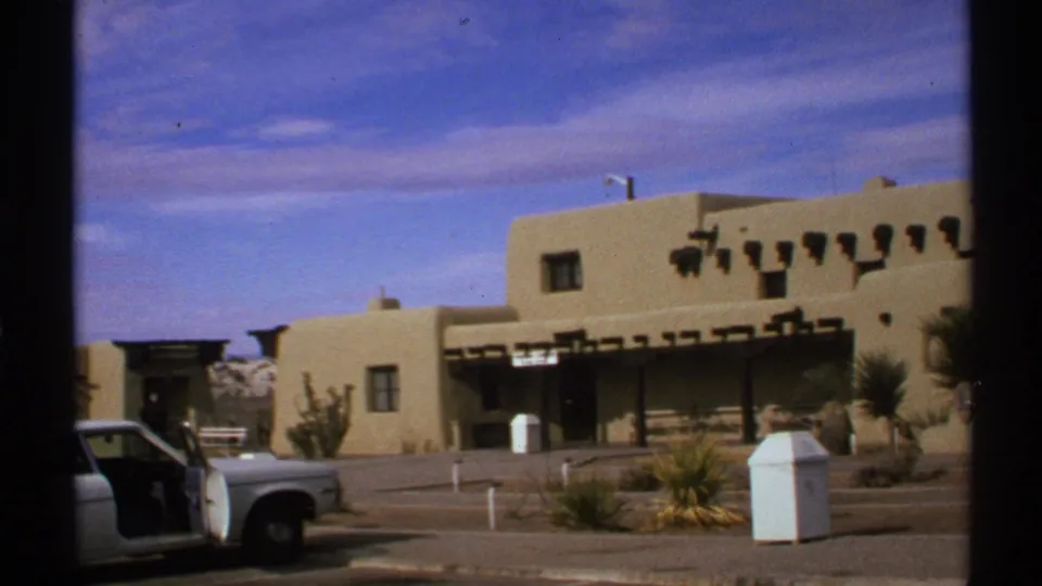 Wider 1972 New Mexico view of the White Sands visitor center area with a car and open door in the foreground.