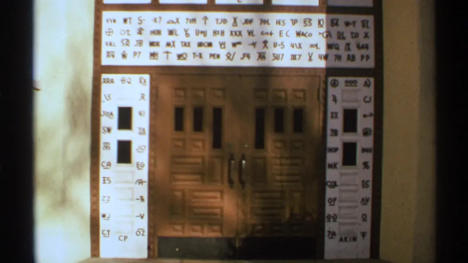 The wooden doorway remains centered while handwritten symbols and numbers are projected across the top and side panels.