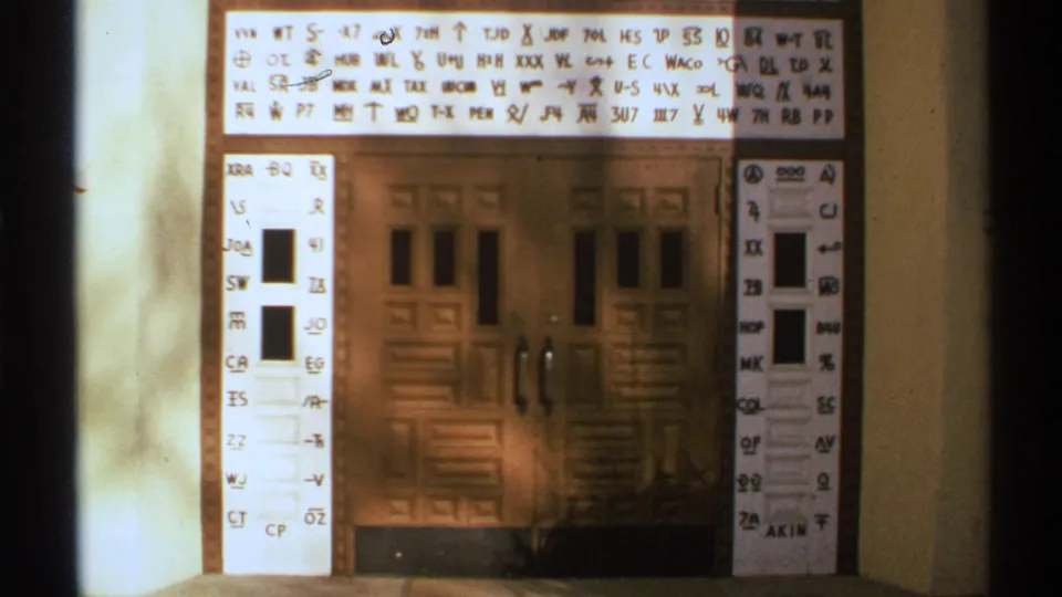 A warm, soft 8mm view shows the double door beneath bright handwritten chart markings and side columns of symbols.