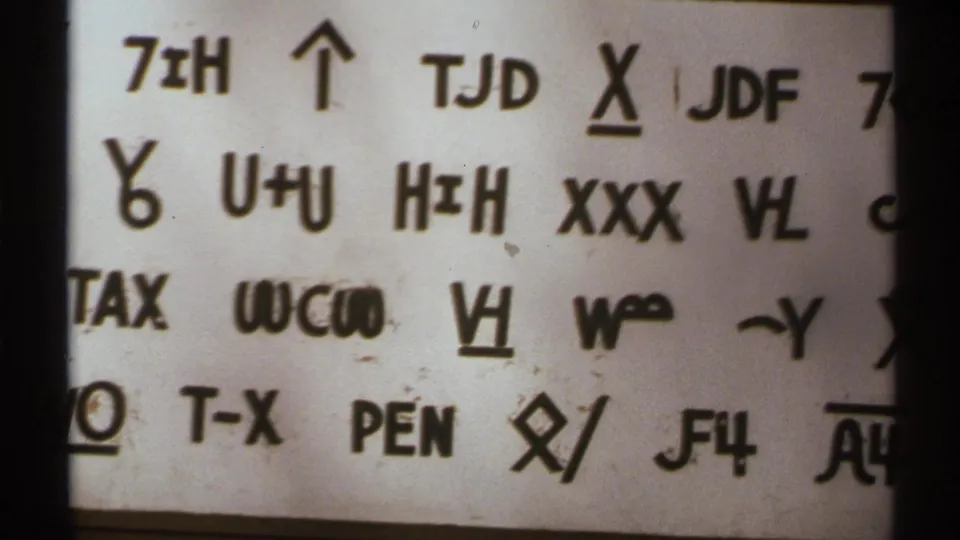 Close 1972 New Mexico 8mm frame showing another section of the unidentified symbol-and-letter sign.