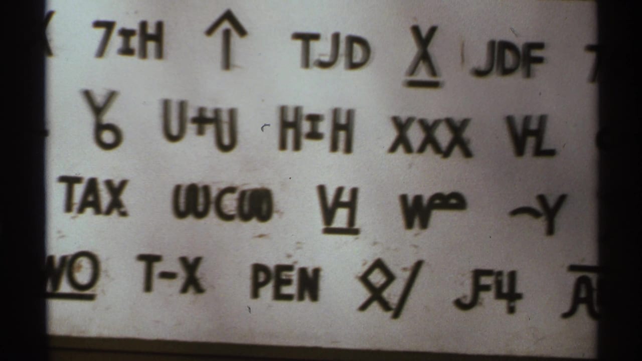 Close-up of black handwritten symbols and letters on white paper.
