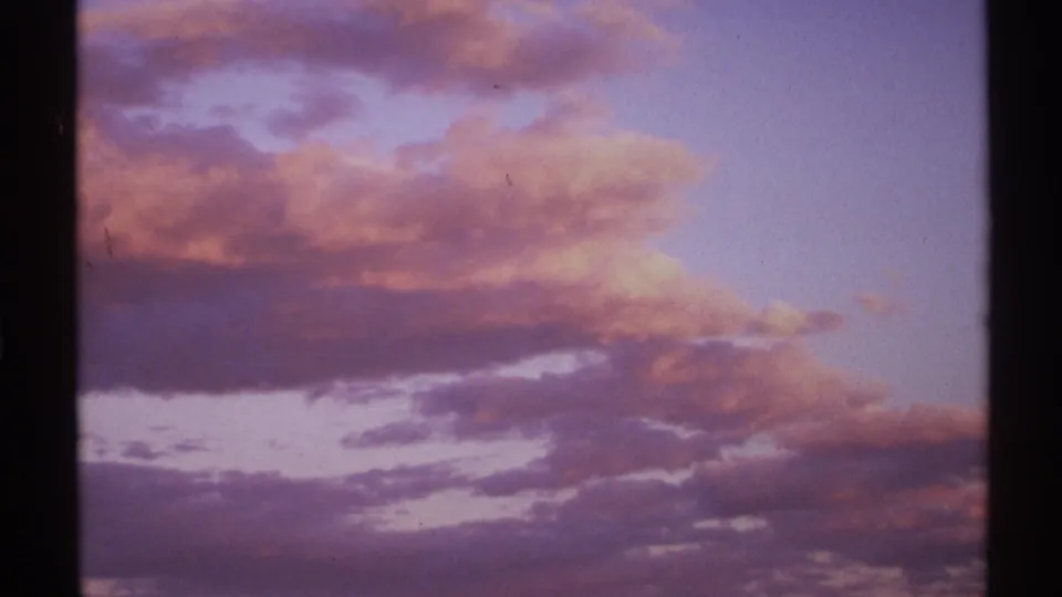 1972 New Mexico home-movie frame of a sunset sky with broad purple cloud layers and pink-orange highlights near dusk.