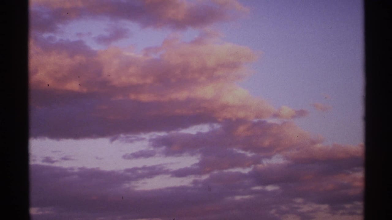 Purple and red twilight clouds across a darkening sky with 8mm film borders.