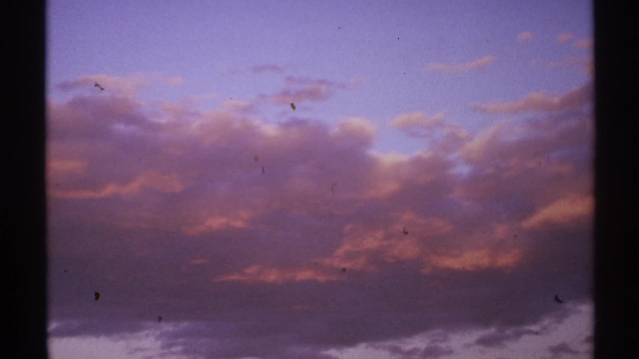 Purple and pink sunset clouds framed by dark 8mm film edges.
