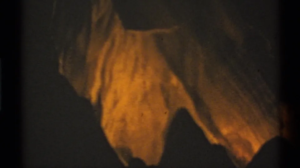 A close 8mm view of rough cavern stone, warmly illuminated against the surrounding dark interior.