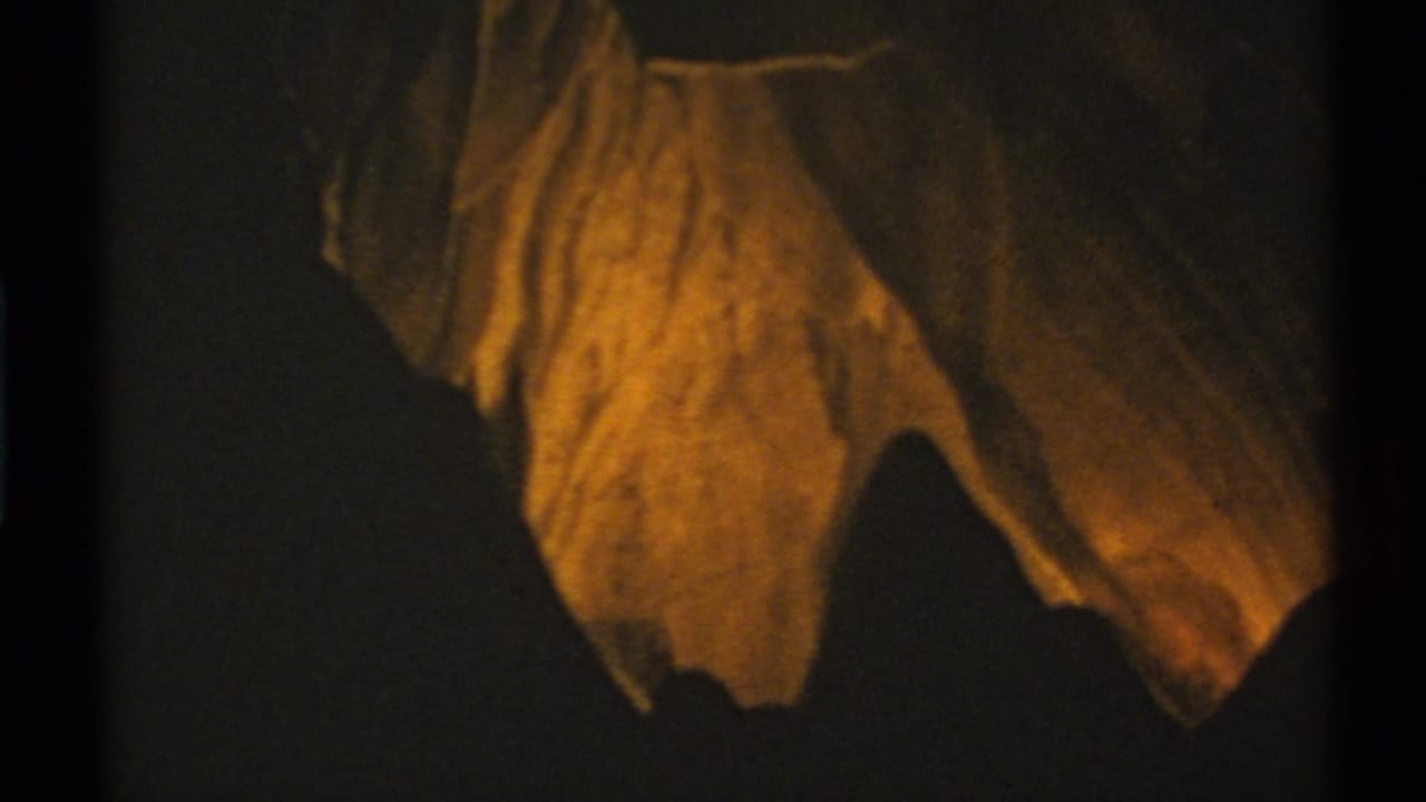 Hanging cave formation glows orange against a nearly black background.