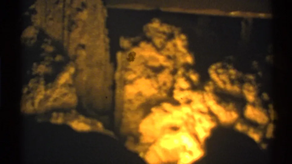 New Mexico cave interior on 8mm film, showing a lit floor area, vertical rock column, and dark surrounding walls.