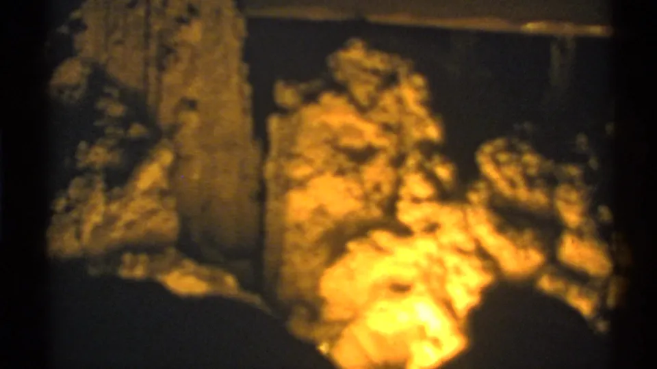 1972 New Mexico cave view with illuminated stone clusters and a darker vertical formation in the foreground.