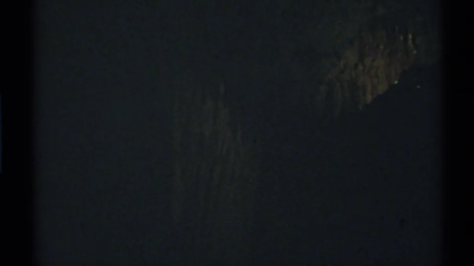 1972 New Mexico 8mm frame where a barely visible textured form sits in a dark, grainy nighttime view.