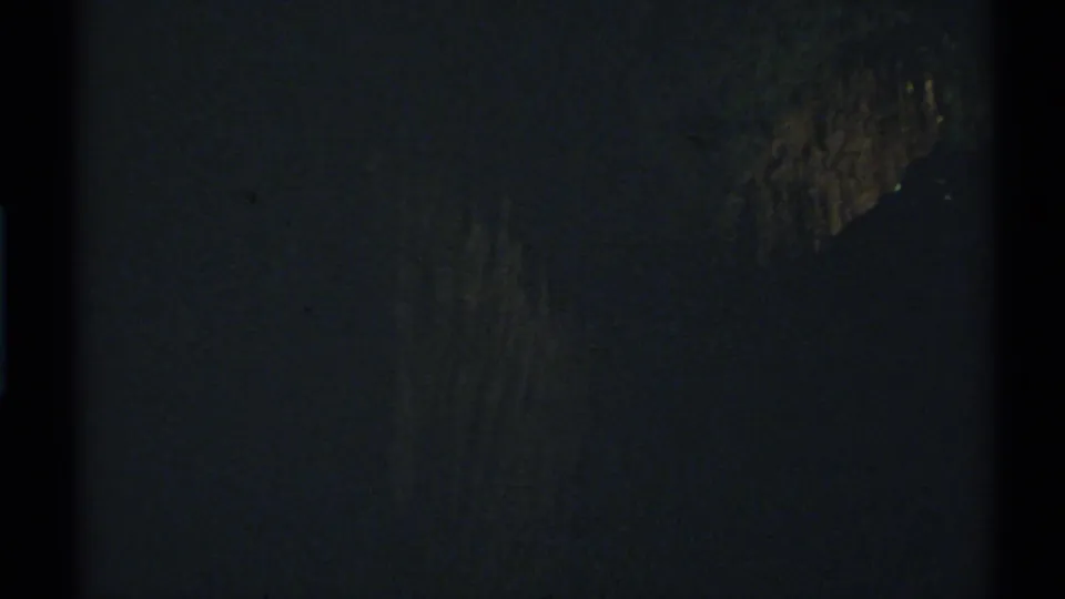 1972 New Mexico 8mm night frame showing dim yellow-brown highlights on an unclear tree or rock-like shape.