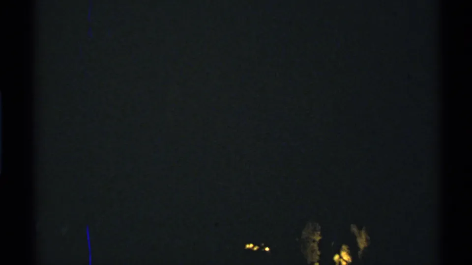 Underexposed 8mm frame from 1972 New Mexico with small blurred lights low in the dark scene.