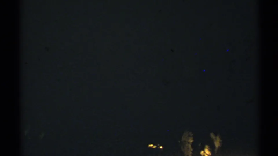 Dark 1972 8mm frame with faint lights or rock shapes barely visible against heavy shadow.