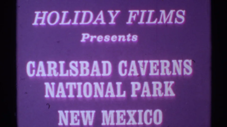 Closer 8mm view of the Holiday Films Carlsbad Caverns National Park title card, tinted purple with soft edges.