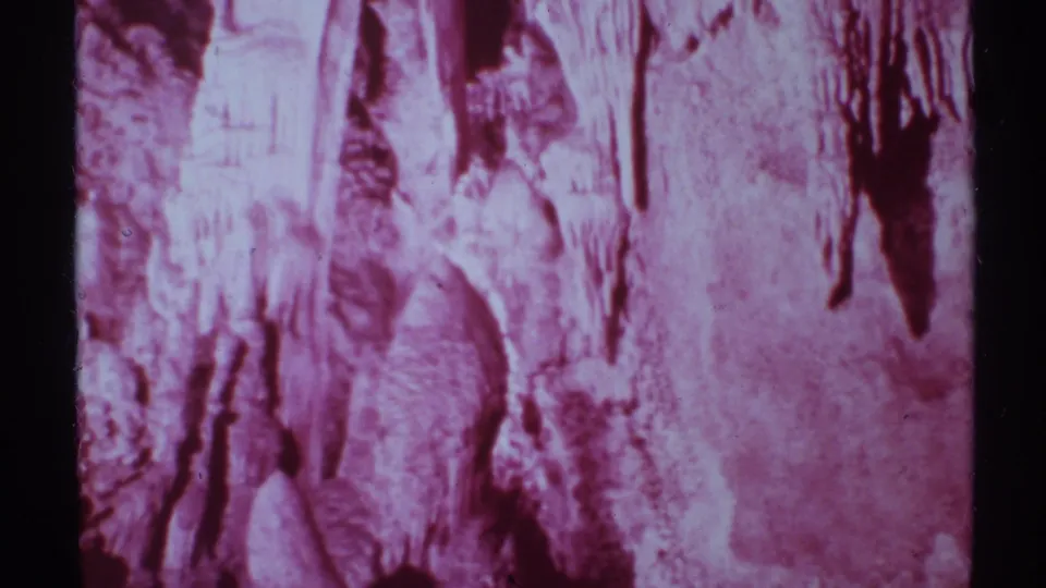 Carlsbad Caverns interior view in red-purple 8mm color, showing textured rock walls and hanging formations.