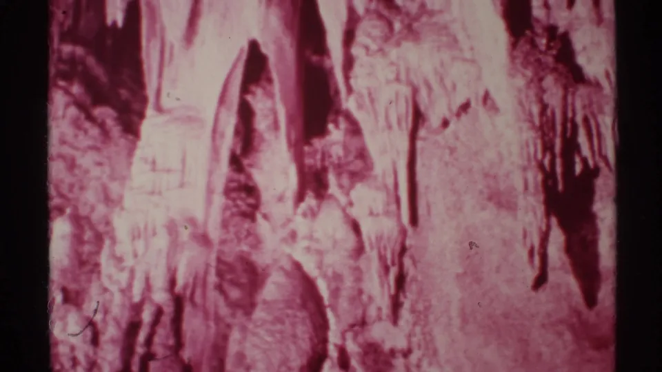 1972 New Mexico 8mm frame showing a close visitor-shot view of pink cave formations and vertical mineral textures.