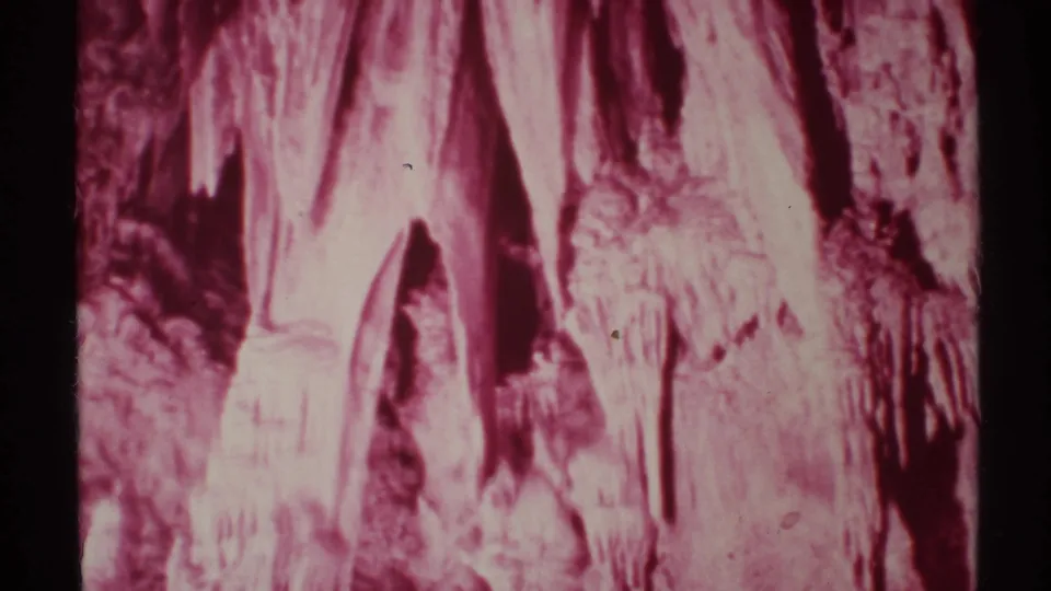 1972 New Mexico 8mm home-movie frame looking upward at stalactites and rough cave textures with a strong red color cast.
