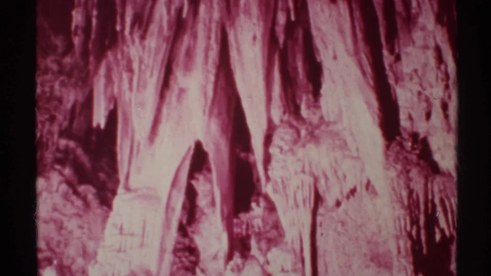 1972 New Mexico cave interior frame showing pale stalactites against darker rock recesses in grainy 8mm footage.