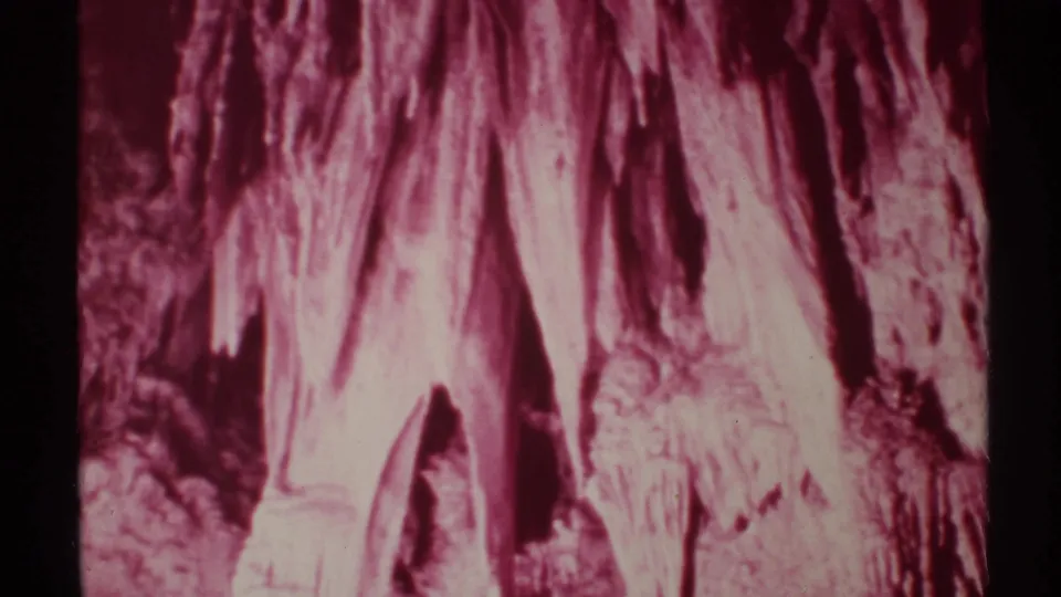1972 New Mexico 8mm frame with a closer handheld view of stalactites, rough cave walls, and reddish aged-film color.