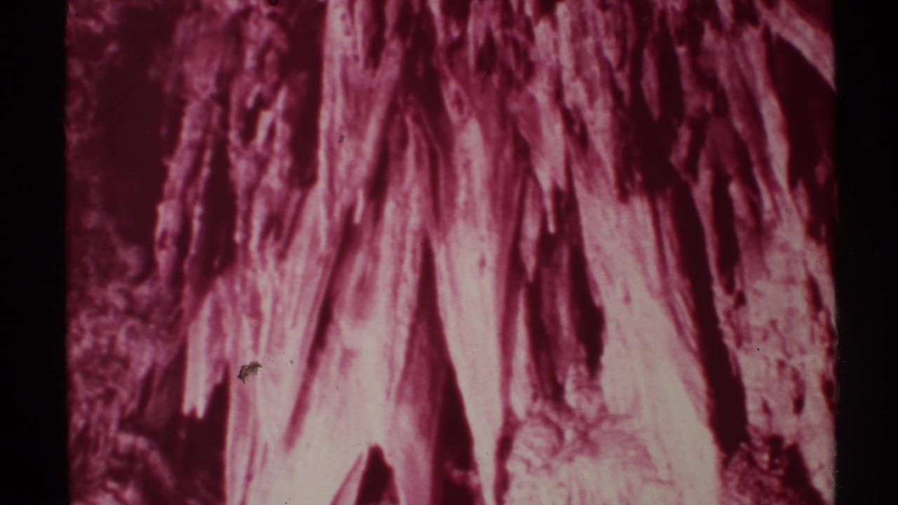Red-tinted cave formations filling the frame with dark film borders.