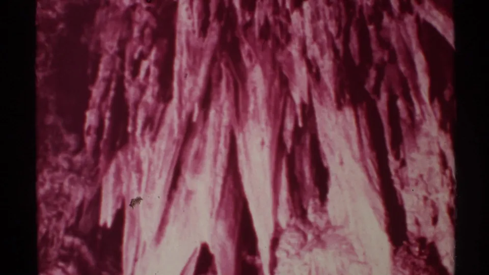 Close view of red-toned cave wall and hanging mineral-like formations in 1972 New Mexico 8mm footage.