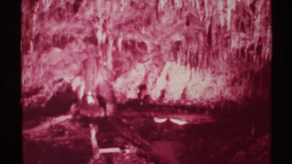 Red-lit New Mexico cavern formations fill this 1972 8mm frame, with dark scan borders and soft home-movie texture.