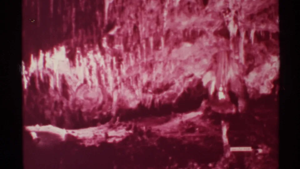 1972 8mm New Mexico footage shows red and white illuminated cave formations with soft grain and dark frame edges.